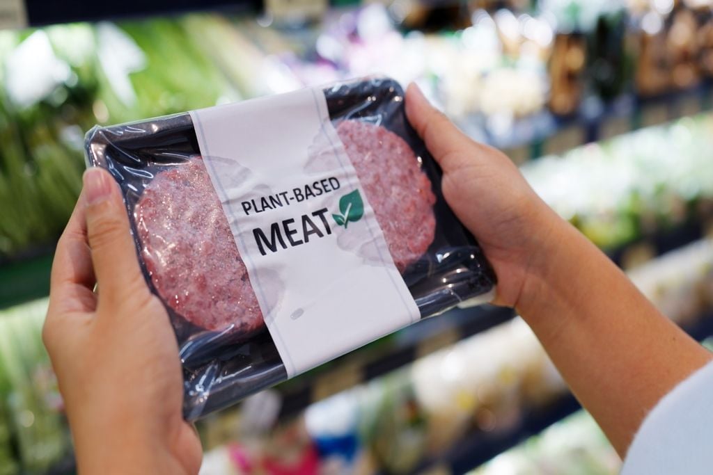 persona con una bandeja de carne vegetal en sus manos, en un ambiente de supermercado