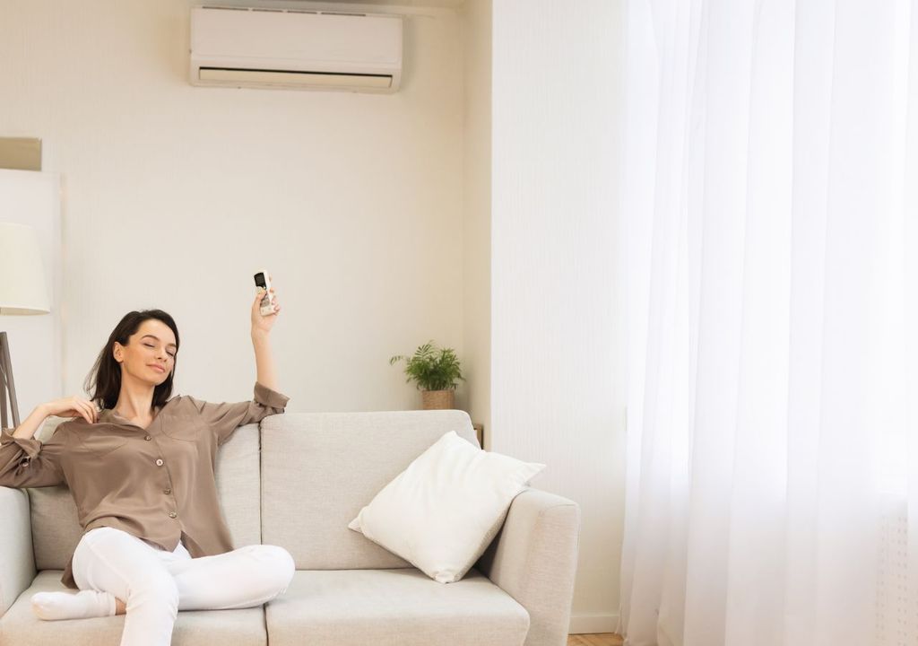 Mujer encendiendo el aire acondicionado Mujer encendiendo el aire acondicionado