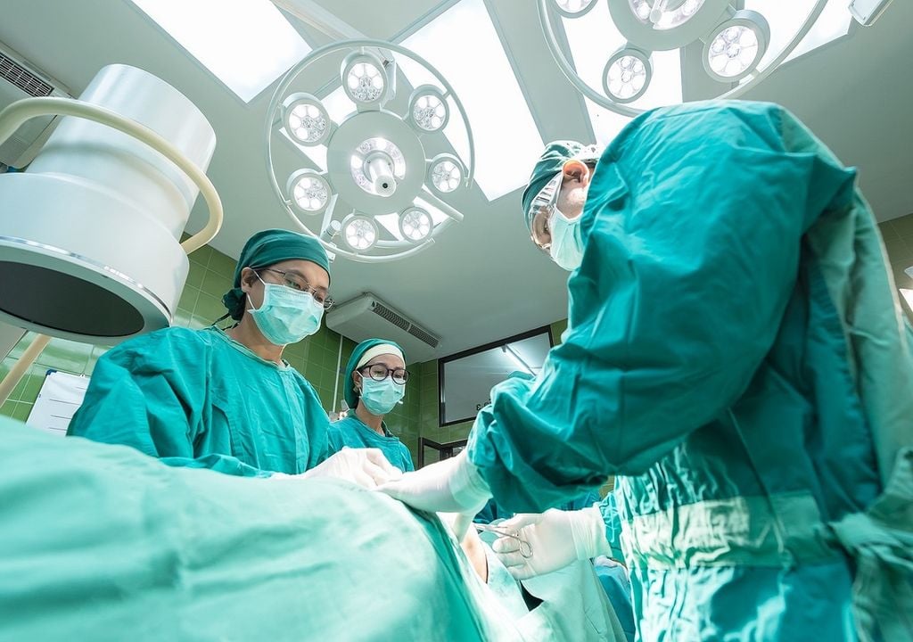 Cirurgiões na sala de operações com paciente Cirurgiões na sala de operações com paciente