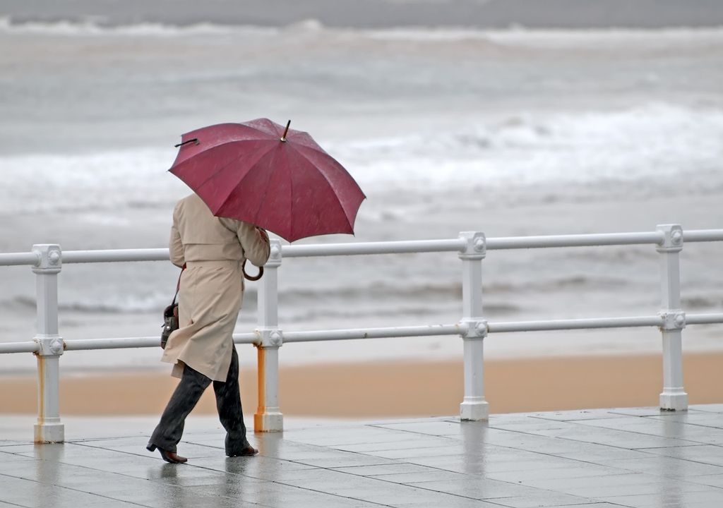 persona caminando con paraguas en un día de lluvia en el borde costero