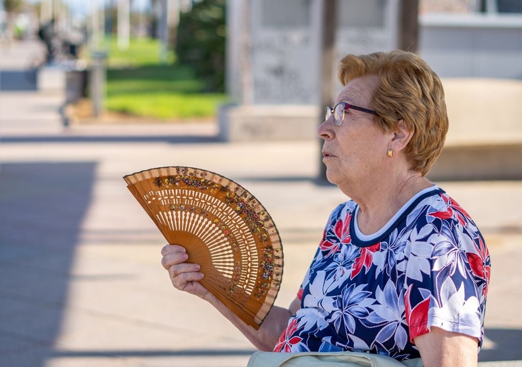 persona adulta mayor abanicándose en un día de altas temperaturas