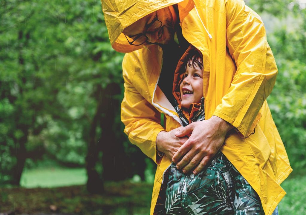 Padre con su hijo bajo la lluvia impermeable amarillo