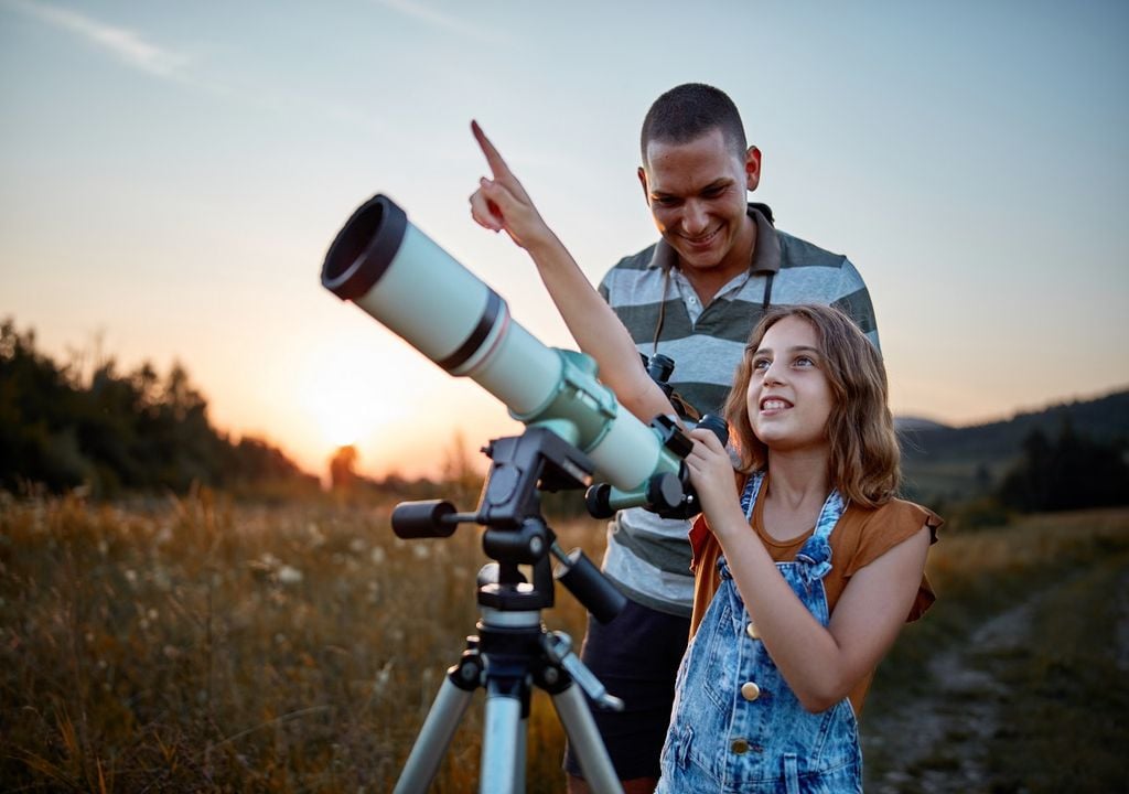 Padre con su hija y telescopio fondo campo