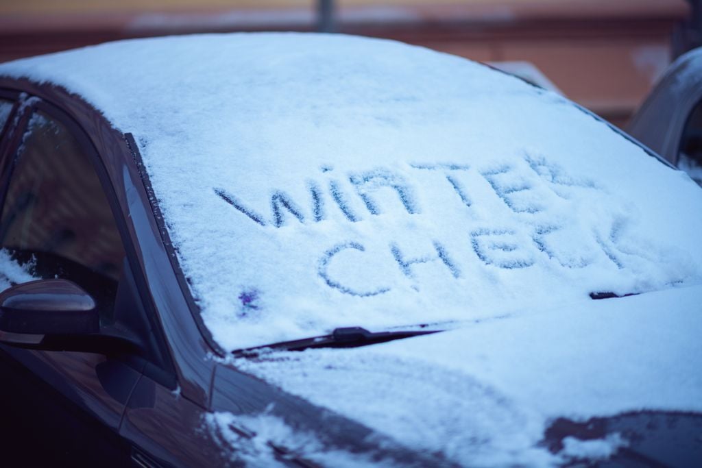 snowy car windshield with winter check inscription