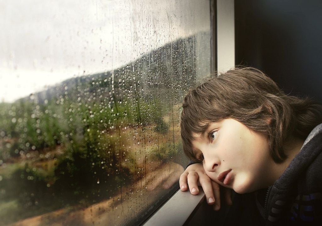 Rapaz à janela contempla a chuva lá fora Rapaz à janela contempla a chuva lá fora