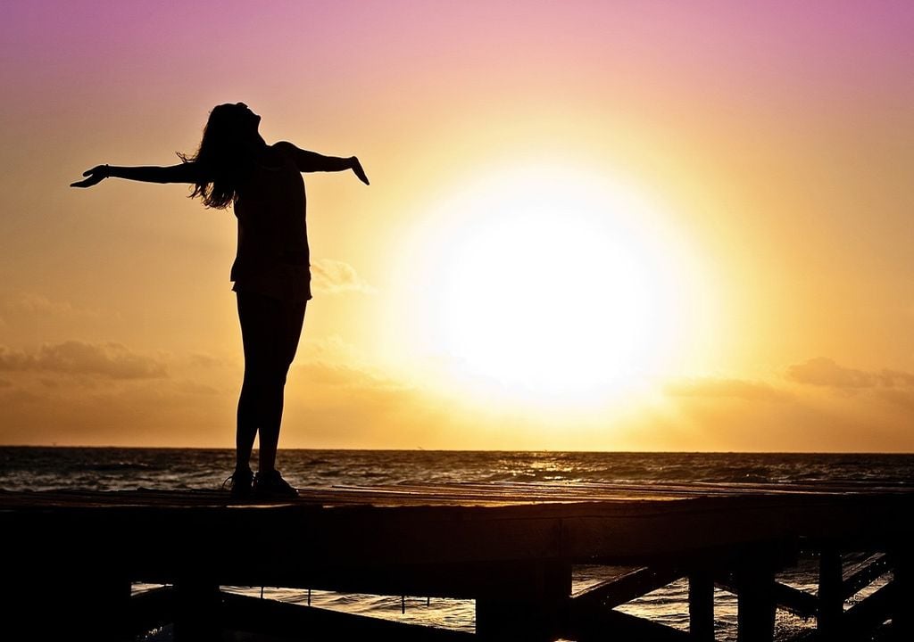 mulher de braços abertos junto ao mar e ao por do sol mulher de braços abertos junto ao mar e ao por do sol