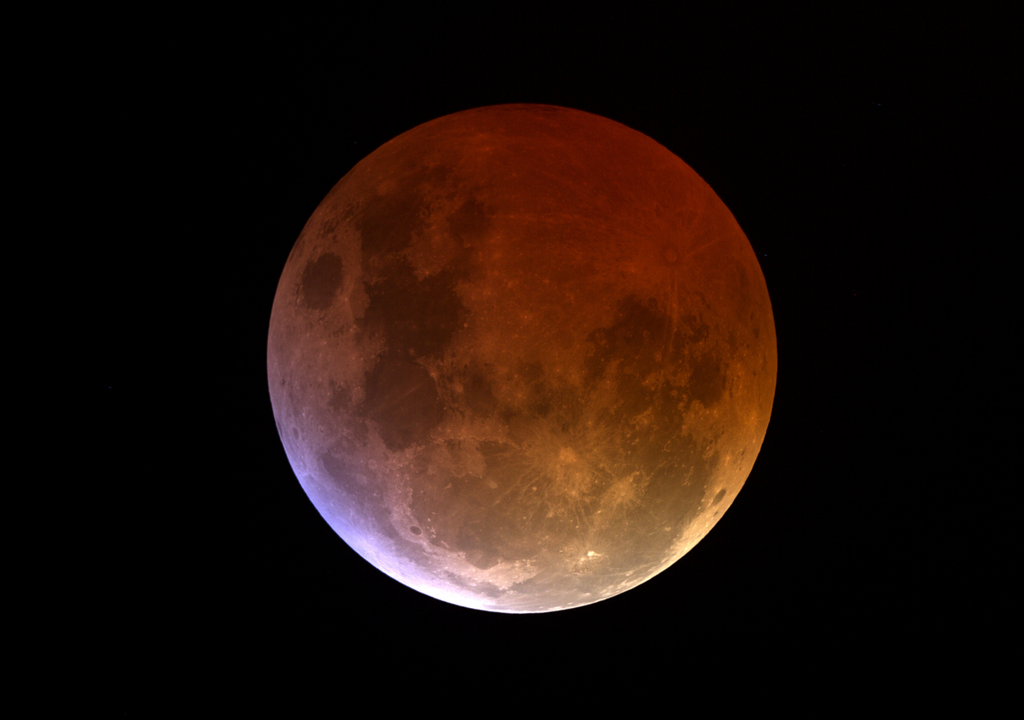 A parte iluminada da Lua em um eclipse lunar parcial fica avermelhado por causa da refração devido à atmosfera terrestre.