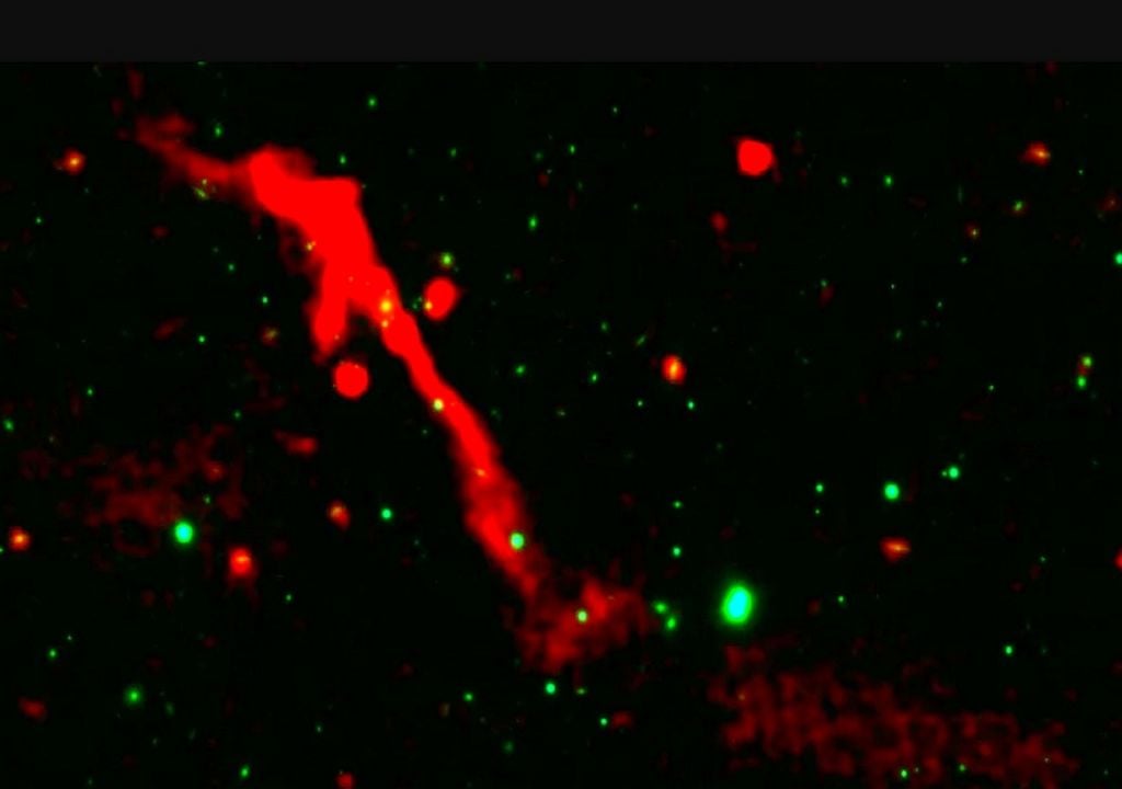 Agujero negro supermasivo en J1007+3540 Representado como una estructura filamentaria de emisiones de radio en tonos rojos, un chorro colosal de energía expulsado por un agujero negro supermasivo evidencia la reactivación de su núcleo galáctico tras un prolongado periodo de inactividad. Crédito de la imagen: LOFAR / Pan-STARRS / S. Kumari et al.