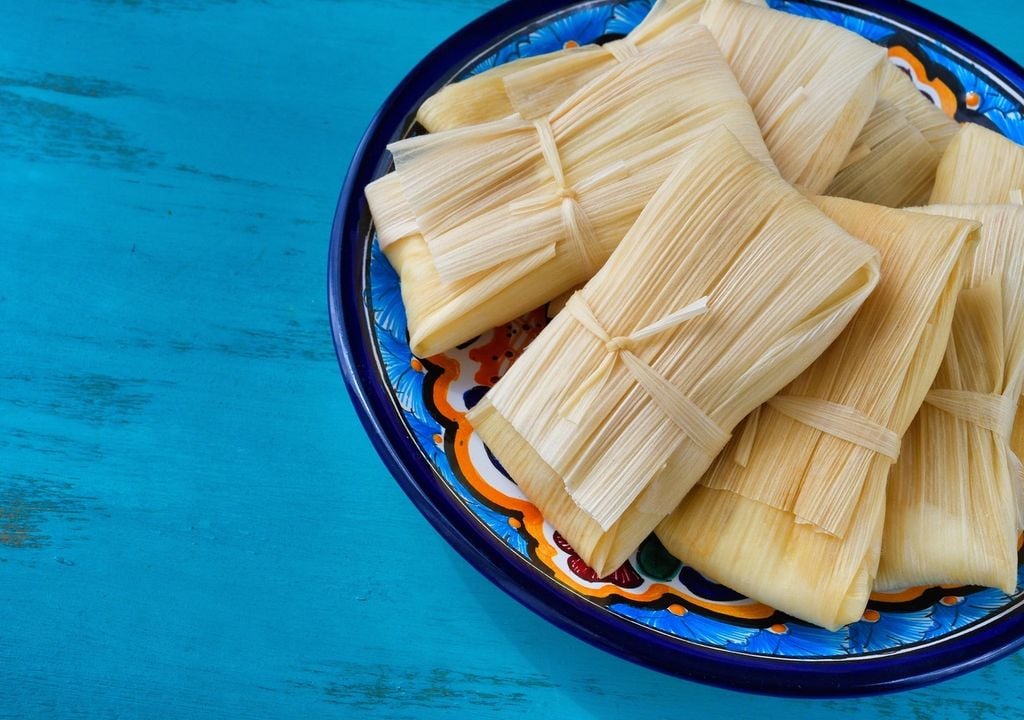 helote El tamal es un alimento que tiene como base la masa de maíz, relleno de diversos ingredientes, cocido en un paquete de hojas vegetales.