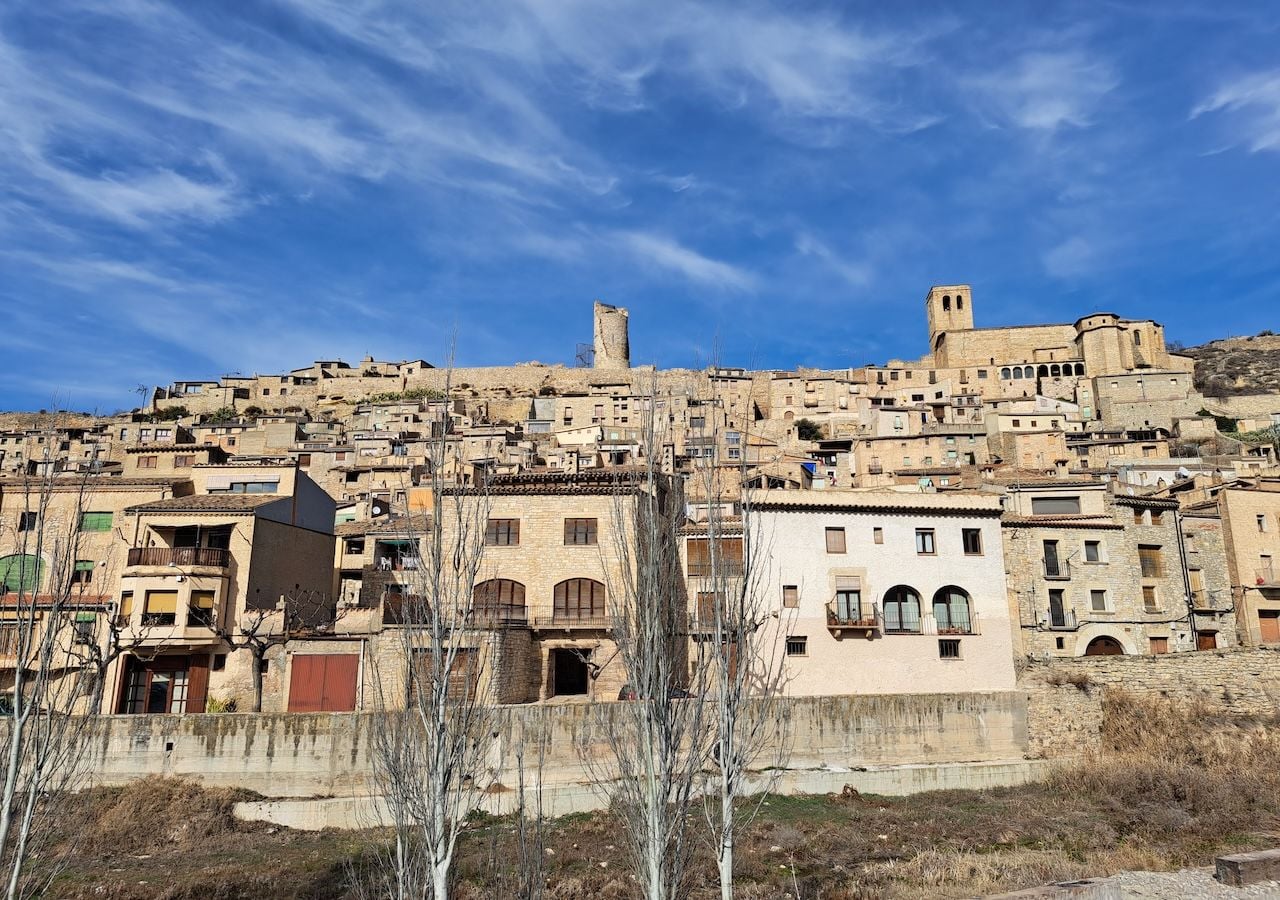 Vista aérea de Guimerà, donde las casas de piedra se escalonan con armonía sobre la ladera, revelando el característico desnivel que define este intacto pueblo medieval catalán.