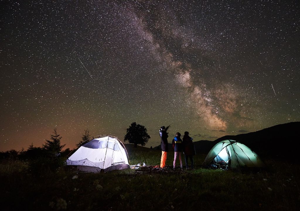 Familia de camping mirando las estrellas de noche, Vía Láctea, carpas iluminadas Familia de camping mirando las estrellas de noche, Vía Láctea, carpas iluminadas