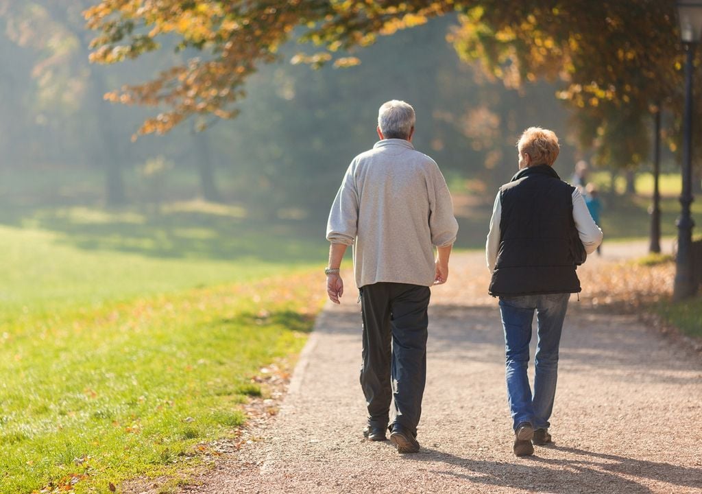 personas de la mejor edad caminando en un parque otoñal