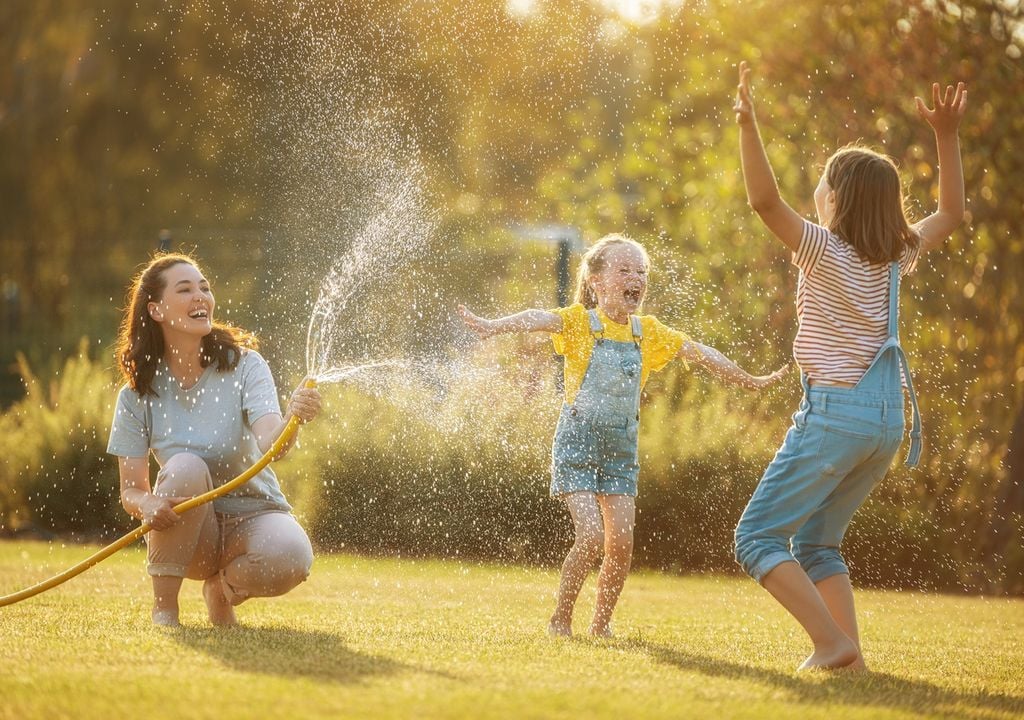 familia jugando con agua y una manguera