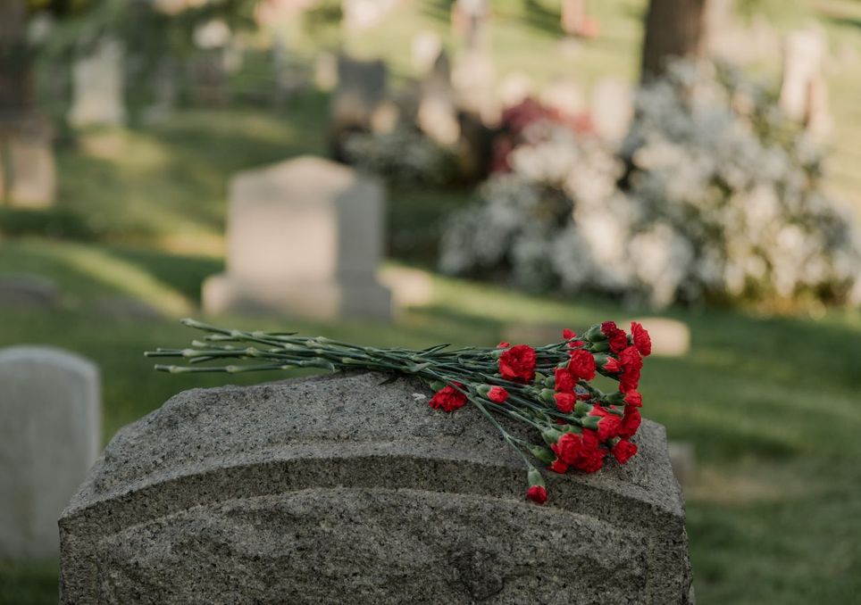 Se cumplen 5 años desde que la COVID-19 paralizó al mundo. ¿Aprendimos lo suficiente para futuras pandemias? Claveles sobre sobre lápida en un cementerio