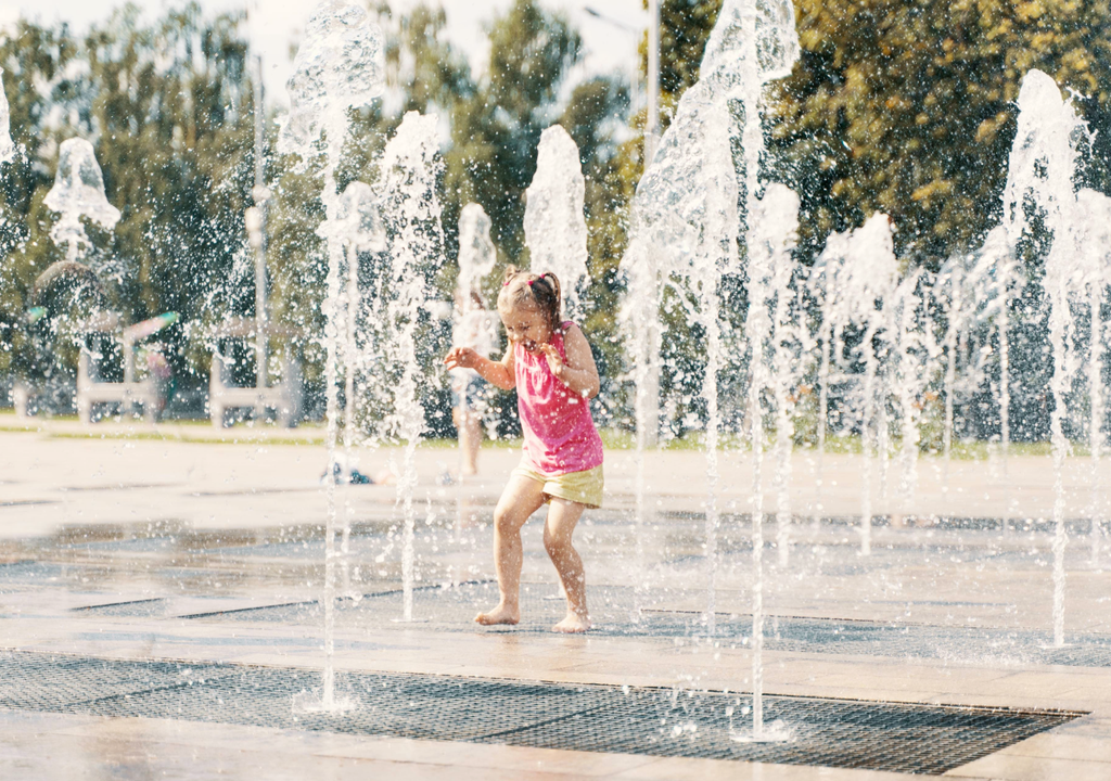 niña jugando entre los chorros de agua de una pileta niña jugando entre los chorros de agua de una pileta