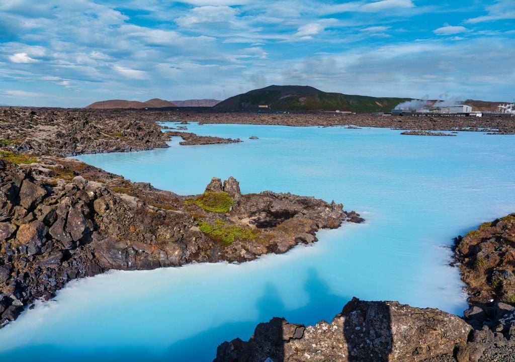 A Lagoa azul encontra-se no meio de um terreno rochoso num campo de lava natural.
