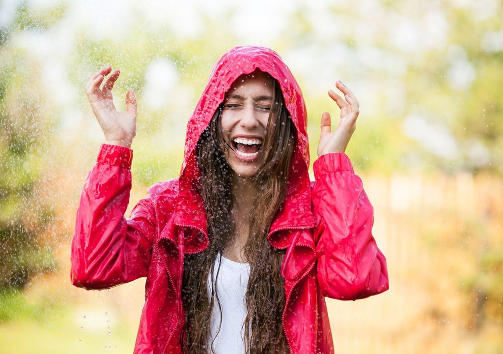 persona con capa de lluvia debajo de un chubasco