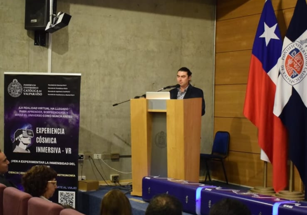 Un representante de la organización presenta la Experiencia Cósmica Inmersiva VR durante su inauguración en el Auditorio del Campus Curauma de la PUCV, acompañado por autoridades y comunidad universitaria.