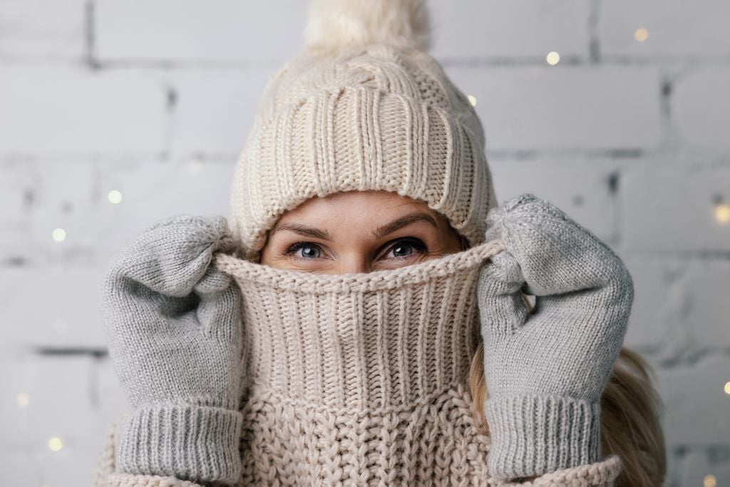 woman hiding face in wool winter sweater