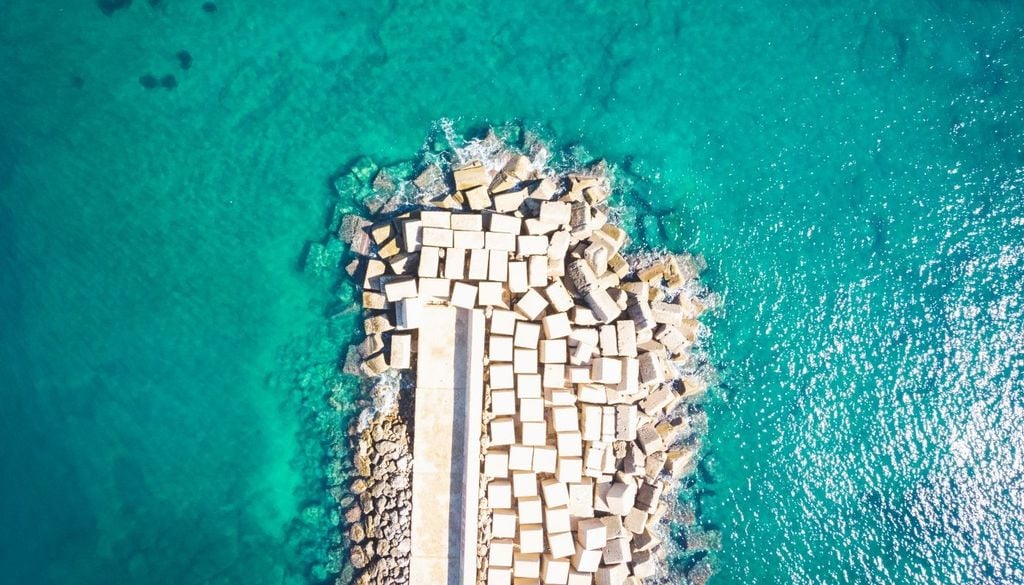 Queste strutture operano modificando l'idrodinamica locale, riducendo l'altezza delle onde del 30-50% in condizioni moderate, creando zone di calma dietro di sé dove la sabbia può accumularsi in "salienti", ossia piccoli istmi di spiaggia.
