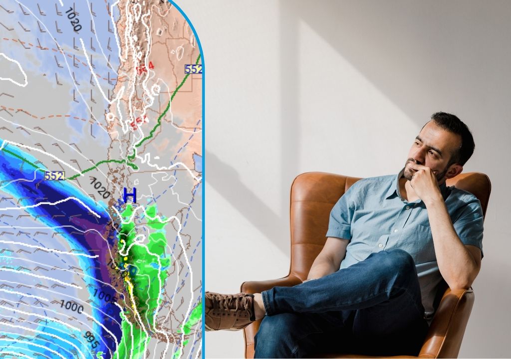 Persona pensando, sentada en un sillón, mirando en dirección a un mapa meteorológico de lluvias