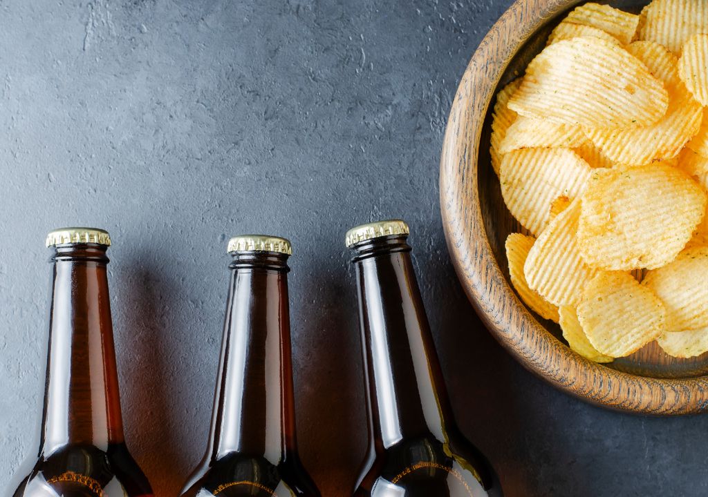drei verschlossene Bierflaschen und industriell hergestellte Kartoffelchips