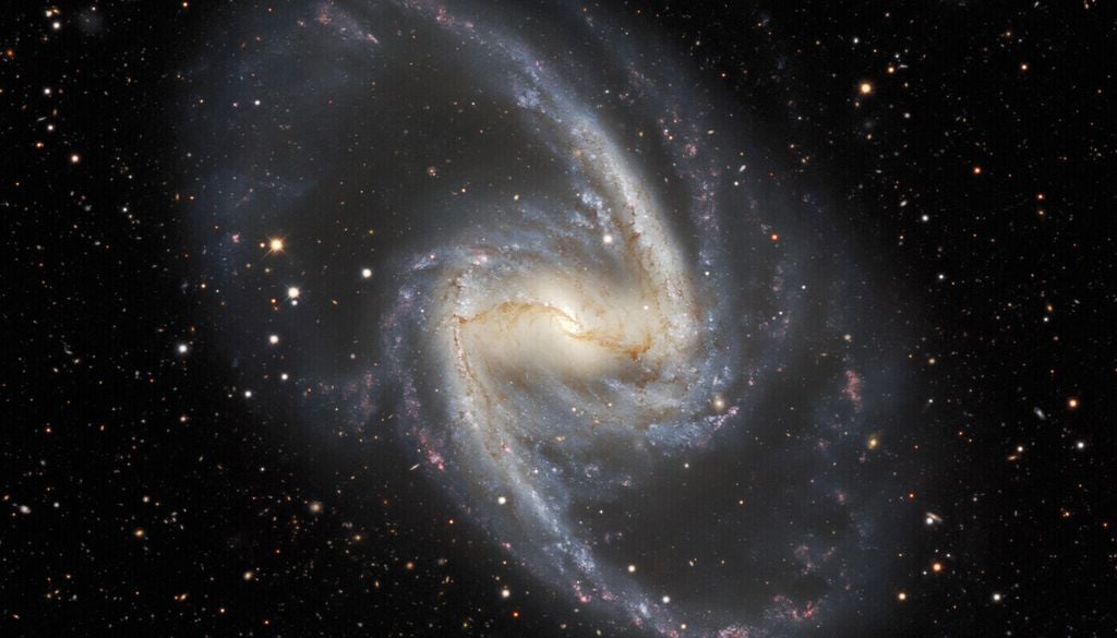 Der zentrale Balken der Großen Balkenspiralgalaxie (NGC 1365) beeinflusst die Sternentstehung in der gesamten Galaxie und beheimatet ein supermassereiches Schwarzes Loch, das hinter zahlreichen neu entstandenen Sternen verborgen liegt. Der zentrale Balken der Großen Balkenspiralgalaxie (NGC 1365) beeinflusst die Sternentstehung in der gesamten Galaxie und beheimatet ein supermassereiches Schwarzes Loch, das hinter zahlreichen neu entstandenen Sternen verborgen liegt. Bild: Dark Energy Survey/DOE/FNAL/DECam/CTIO/NOIRLab/NSF/AURA