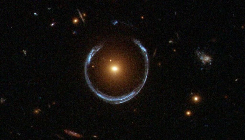 Weil sie weitestgehend geschlossen sind, stellen Einsteinringe eine Sonderform der Gravitationslinse dar, hier ein Einsteinring (blau) um die Galaxie LRG 3-757 (Lichtpunkt in der Mitte). Bild: ESA/Hubble & NASA