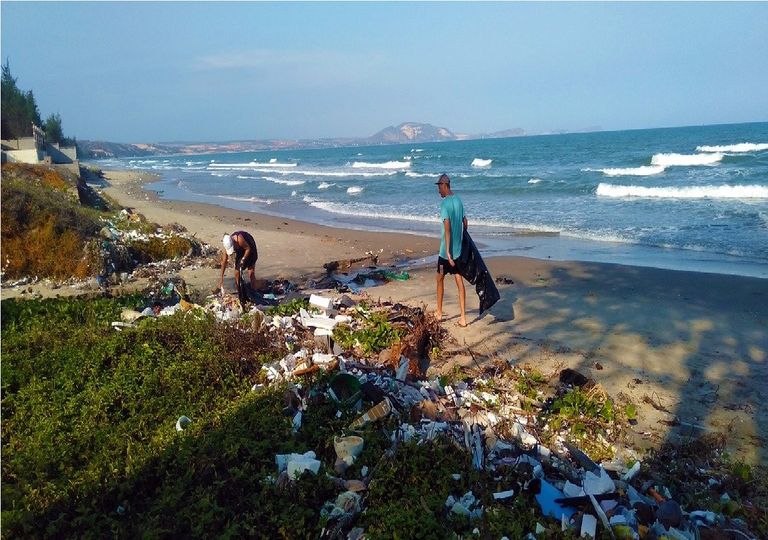 Personas recogiendo basura plástica en una playa Personas recogiendo basura plástica en una playa