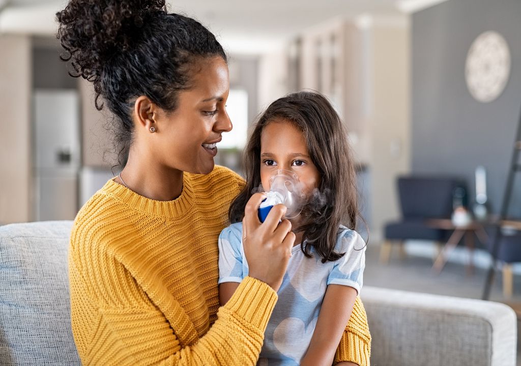 Madre y su hija con inhalador para asma fondo de living