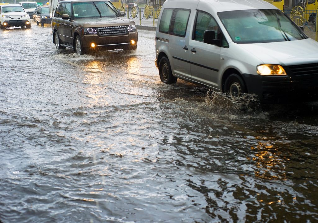 Autos circulando en una calle inundada con agua de lluvias