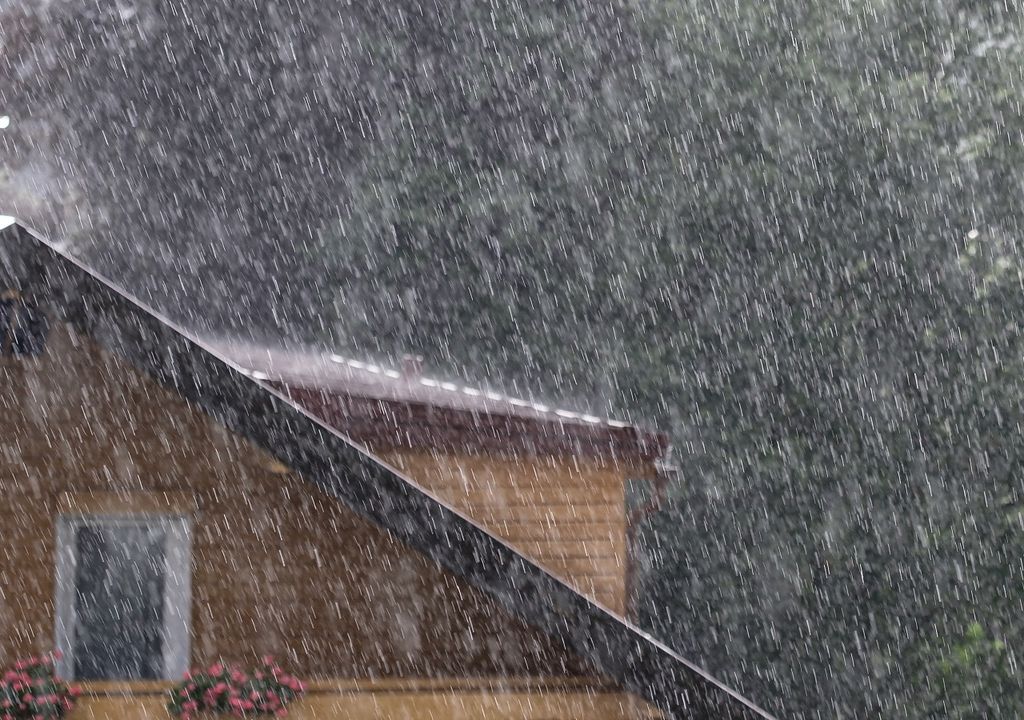 Parte de una casa visible por detrás de una lluvia copiosa