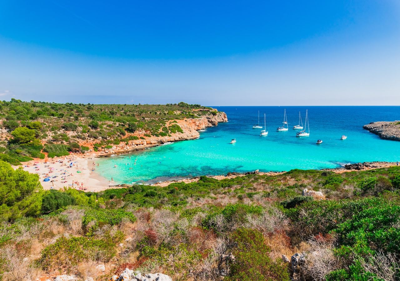 Panorámica de Cala Varques con su característico arco natural de roca al fondo, una formación esculpida por el mar que se ha convertido en icono de esta cala virgen del litoral de Manacor.