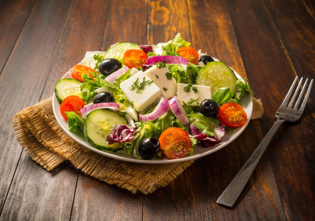 Ensalada de queso fresco, tomates cherry, zapallo italiano y lechugas, sobre mesa