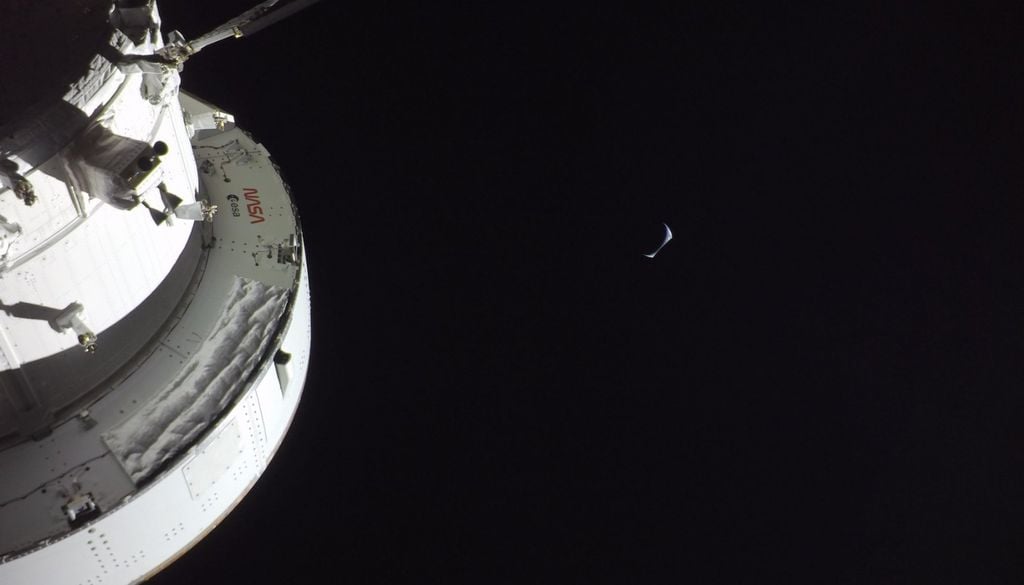 La capsula Orion nel vuoto, con la Luna che occupa gran parte dell'inquadratura e la Terra ridotta a una piccola falce luminosa sullo sfondo. In questa foto si può avvertire la sensazione di isolamento totale di questi astronauti-esploratori. Credits: NASA/JSC
