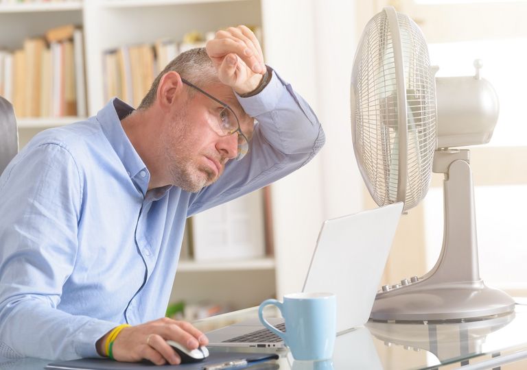 Hombre trabajando en su casa con altas temperaturas Hombre trabajando en su casa con altas temperaturas