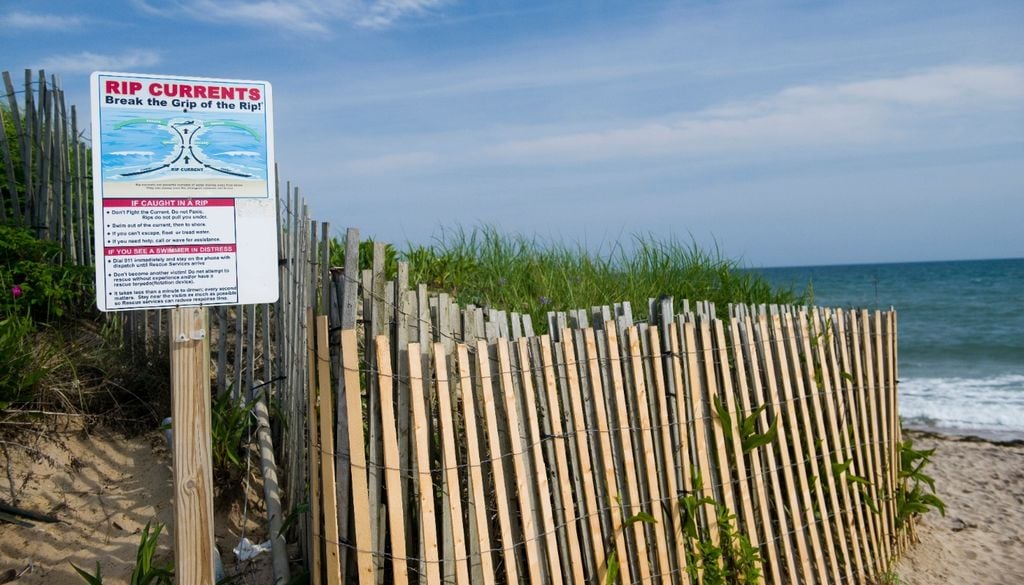 Veduta della spiaggia di Ditch Plains a Montauk, Long Island, New York, negli Hamptons, con un cartello di avvertimento per corrente di risacca