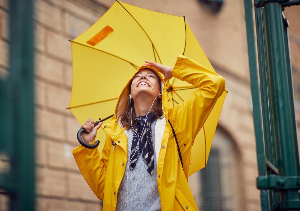 Persona mirando hacia el cielo, con una chaqueta y paraguas amarillo