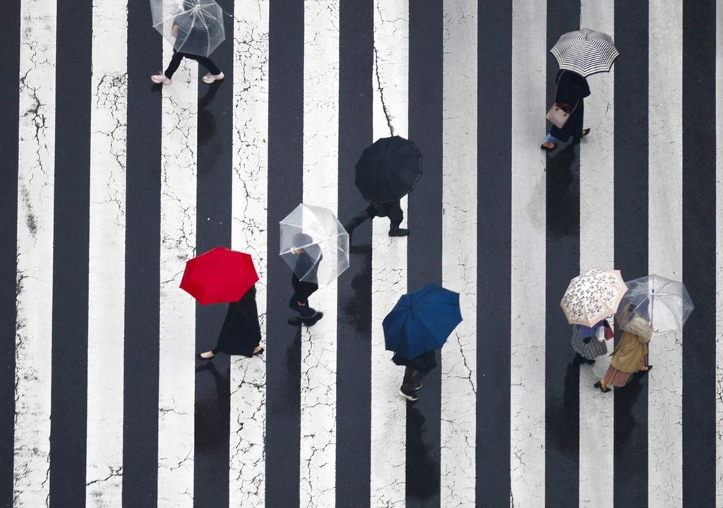 personas con paraguas abierto cruzando por un paso peatonal