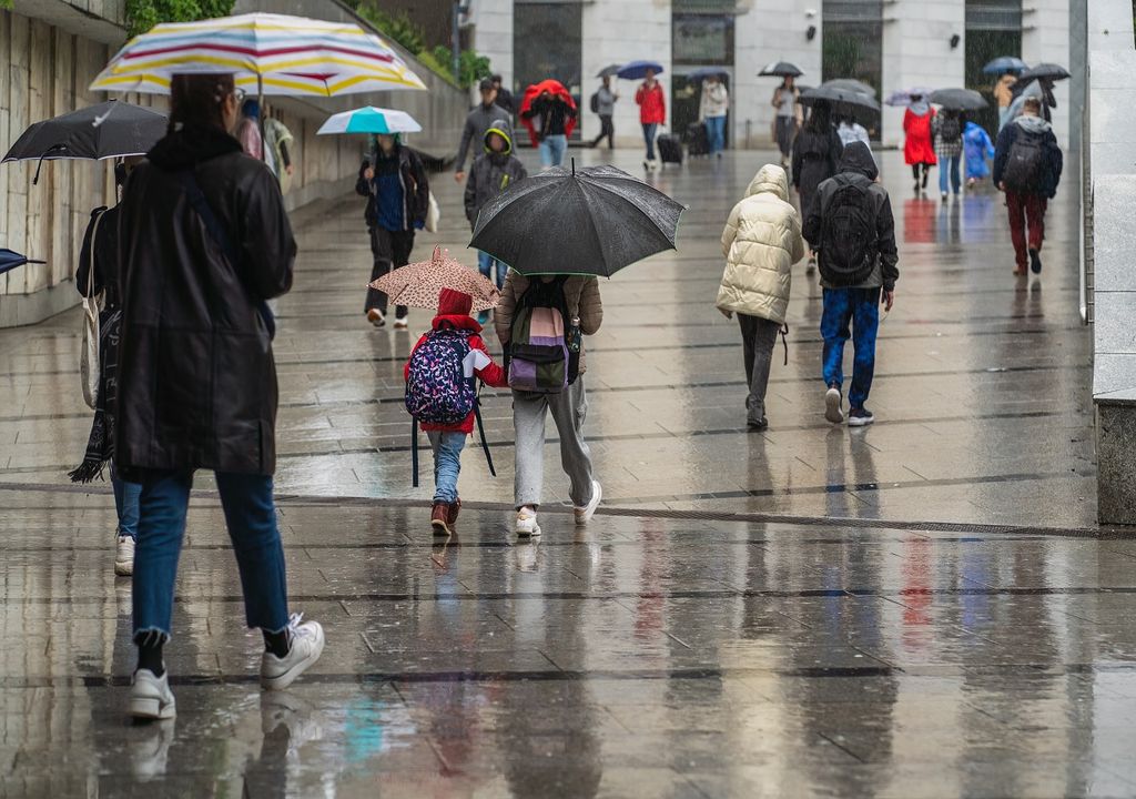 Personas con paraguas caminando bajo la lluvia en el centro de la ciudad
