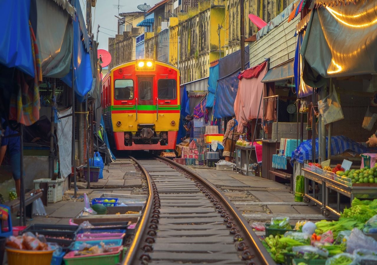 Situado sobre unos 300 metros de vía férrea, este mercado recibe trenes tanto de pasajeros como de carga, conectando directamente con la línea Mahachai–Ban Laem, una de las más antiguas del país.