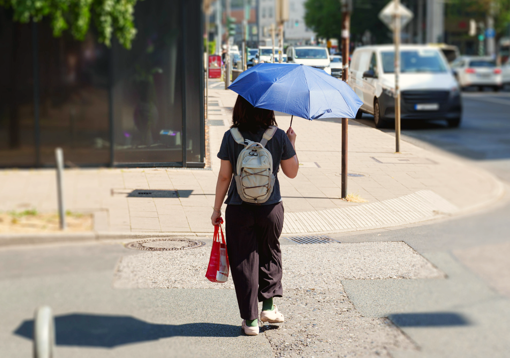 persona con paraguas caminando en una calle durante un día de Sol intenso Suben las temperaturas en Chile, mientras que las lluvias siguen sufriendo la influencia de El Niño.