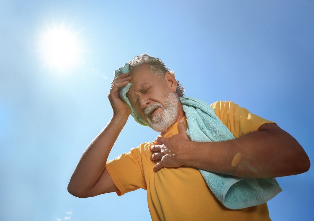 Hombre mayor con calor sofocante fondo cielo despejado y sol