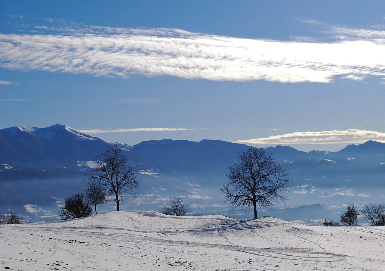 La valle bellunese con le montagne innevate e la foschia e nebbia al piano. Gli ultimi giorni sono stati miti in quota, e una parte di neve si è fusa, e nebbiosi al piano. Sarà simile la situazione in montagna per diversi giorni, condizione ideale per gli sport invernali.