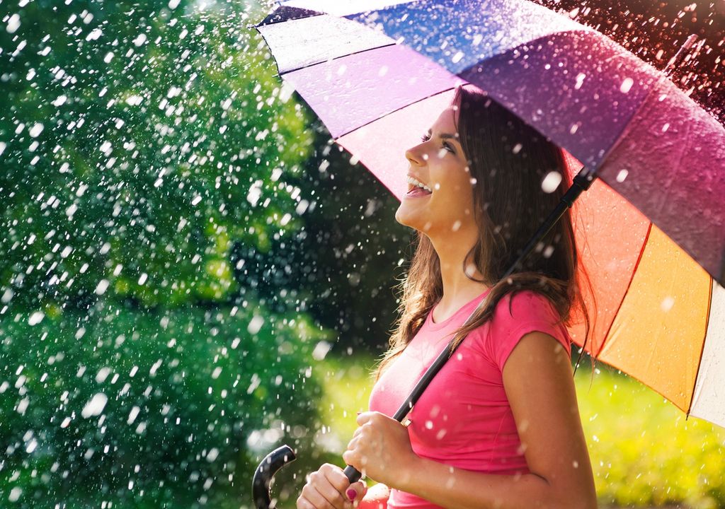 persona de paraguas, vistiendo camiseta, bajo una lluvia de verano