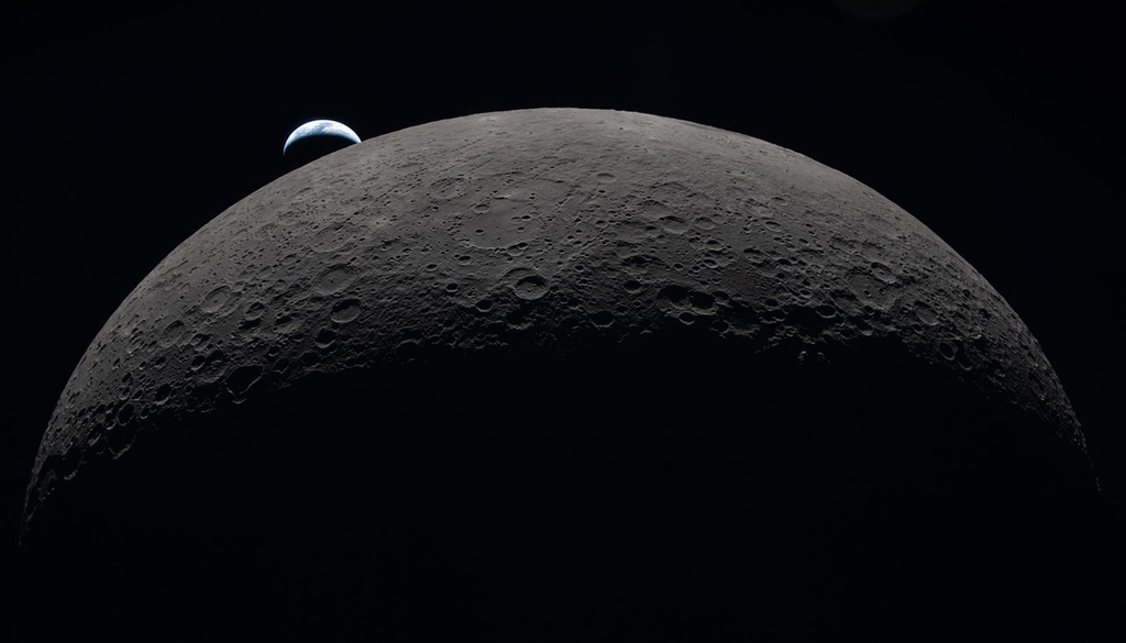 La Luna, de color marrón grisáceo y llena de cráteres, domina el encuadre contra el espacio negro, con una Tierra en fase creciente parcialmente iluminada que se oculta detrás de su borde superior izquierdo. Esta imagen fue tomada por un astronauta de Artemis II desde la cápsula Orion en abril de 2026, mientras la nave espacial pasaba junto a la Luna en su viaje de casi 10 días. La Luna, de color marrón grisáceo y llena de cráteres, domina el encuadre contra el espacio negro, con una Tierra en fase creciente parcialmente iluminada que se oculta detrás de su borde superior izquierdo. NASA
