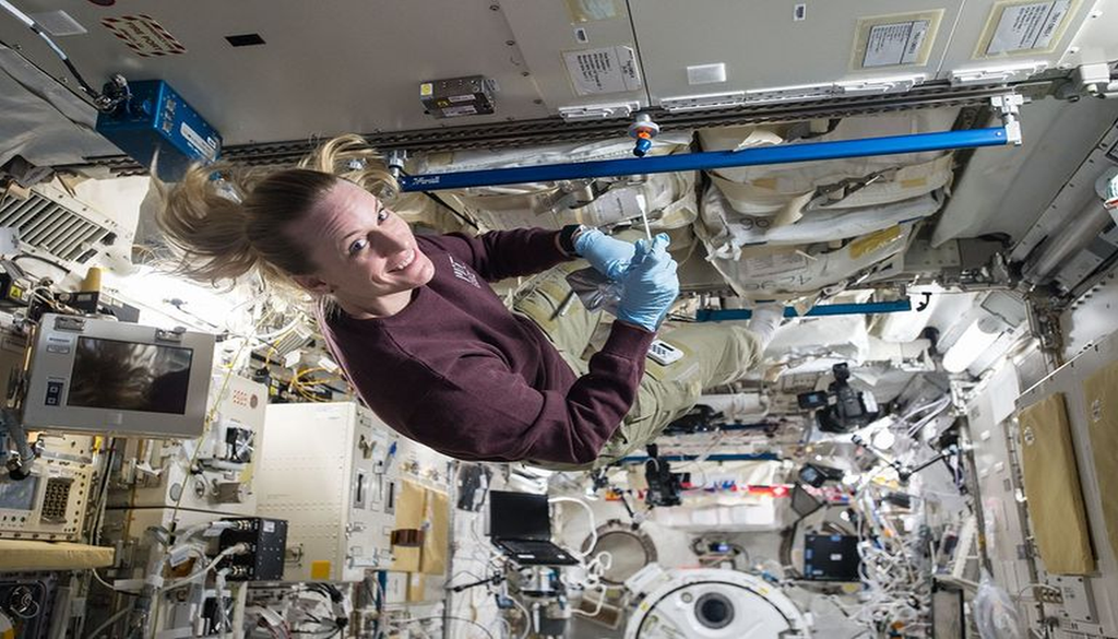 Una astronauta lleva a cabo trabajos científicos a bordo de la Estación Espacial Internacional, flotando en microgravedad y rodeada de equipos y herramientas de investigación. La astronauta de la NASA Kate Rubins recolecta microbios en el Módulo Experimental Japonés a bordo de la Estación Espacial Internacional, el 14 de octubre de 2016. JAXA/Takuya Onishi