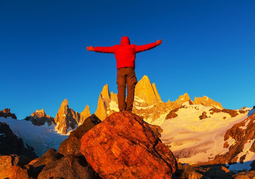 Persona con brazos abiertos contemplando las Torres del Paine.