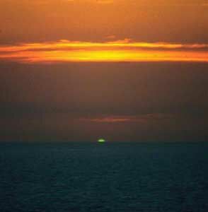 Fig.6 Atardecer en el océano. La luz solar le llega al observador mayoritáriamente del espectro infrarrojo visible dando tonalidades en las nubes y en el cielo rojizas. En el último instante, y antes de ocultarse, los haces verdes llegan a los ojos del observador: es el rayo verde.