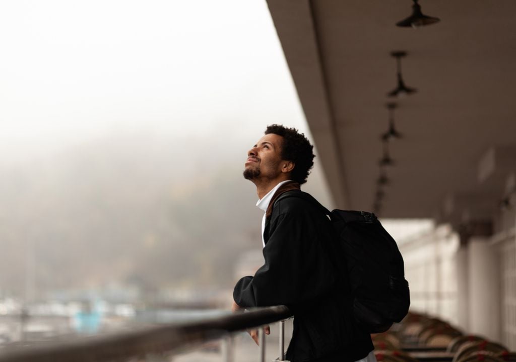 Homem agasalhado e com mochila observando um céu nublado. Homem agasalhado e com mochila observando um céu nublado.